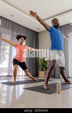 Couple practicing yoga together at home, stretching on mats with focus Stock Photo