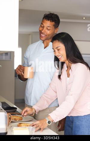 Couple enjoying breakfast together, smiling while making toast in kitchen Stock Photo