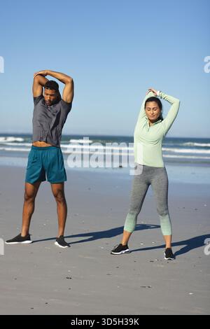 Stretching on beach, couple doing morning exercise by ocean together Stock Photo