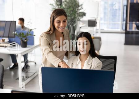 Happy female Hispanic mentor woman standing at young Asian employee Stock Photo