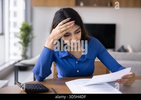 Serious young Indian woman reading legal document Stock Photo
