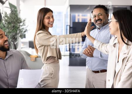 Cheerful successful diverse female coworkers giving high five Stock Photo