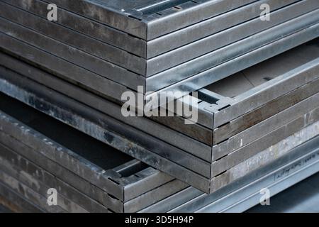 Galvanized metal formwork sheets placed in compact aligned stack showing reinforced borders, straight edges and solid panel bodies prepared for demand Stock Photo