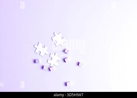 White puzzle pieces and scattered cubes on purple surface symbolize problem-solving, creativity, and contrast between structure and randomness. Stock Photo