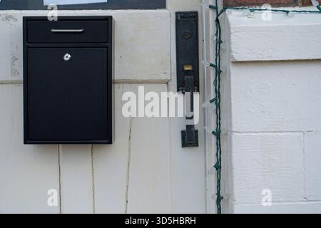Black Mailbox and Handle on a White Wooden Door Stock Photo