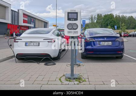 Laajalahti, Espoo, Finland - August 19. 2025: White and blue Tesla Model 3 electric cars parked in shopping center parking lots electric charging stat Stock Photo
