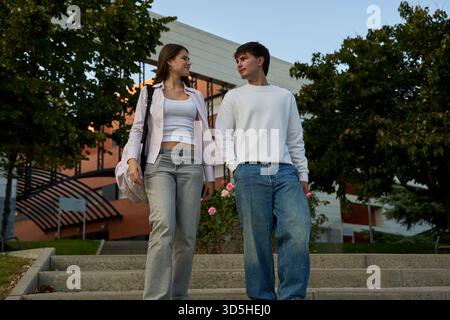 Young couple, college students, walking down university stairs, holding hands, sharing a moment, expressing connection and love Stock Photo