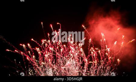 Vibrant Red and Silver Fireworks Exploding Against Night Sky Stock Photo