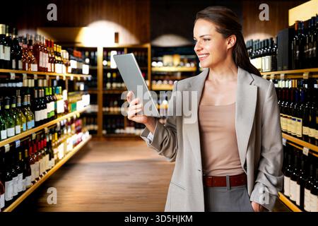 Female professional using digital tablet on background of wine shop. Stock Photo
