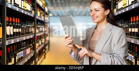 Female professional using digital tablet on background of liquor store. Stock Photo