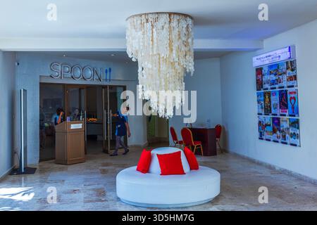 Beautiful view of Spoon restaurant lobby with chandelier white sofa red pillows and staff. Punta Cana. Dominican Republic. Stock Photo