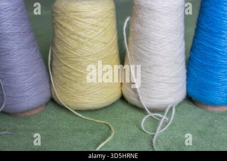 Variety colours of alpaca wool and silk. Cones of multicoloured yarn. Wool threads in a row. Row of blue, white, yellow and grey wool. Knitting hobby. Stock Photo