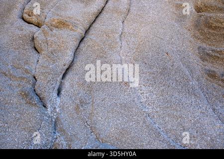 Weathered granite stone texture in gentle daylight, showing subtle cracks and fine grain detail Stock Photo