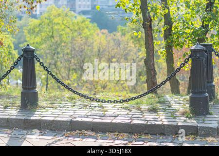 Image shows a serene, inviting hillside park path ascending a green hill The sturdy black metal railing offers security for a peaceful walk amidst aut Stock Photo