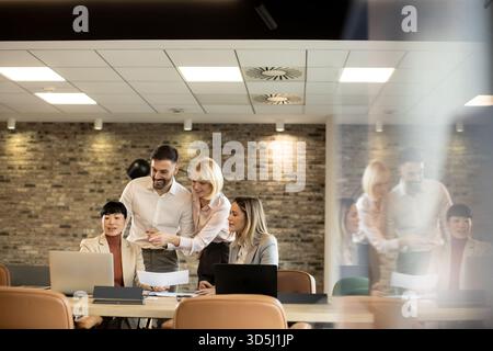A diverse group of professionals gathers around a table in a stylish office, sharing ideas and reviewing documents to spark creativity. Stock Photo