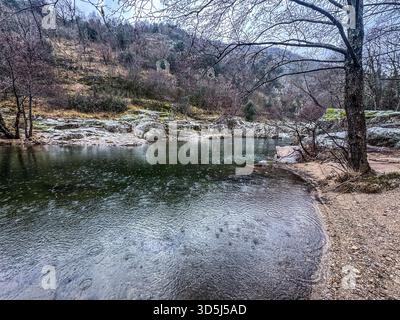 Rain is falling on Chassezac river in a forest, creating beautiful concentric circles on the water surface Stock Photo