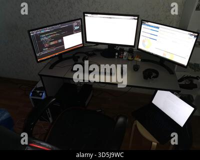 Triple monitor developer workstation with laptop in home office Stock Photo