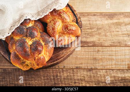 Shabbat Shalom. Bread challah with sesame seeds and poppy seeds on wooden background. Traditional jewish bread for Shabbat and Holidays. Rustic concept. Copy space. Selective focus. Stock Photo
