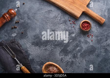 Old meat fork, black plate, black pepper and black pepper and spice mill on an old gray concrete background. Food cooking background and mock up. Stock Photo