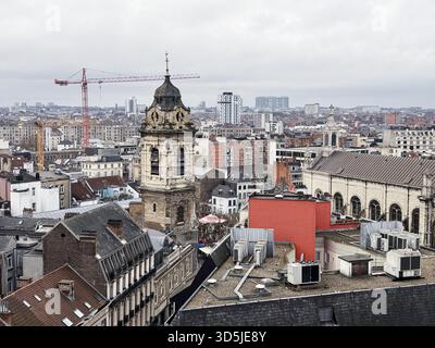 Belgium, Brussels, December 31th, 2024; Construction crane rising above a historic church amidst the rooftops and buildings of brussels, belgium, show Stock Photo