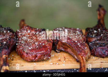 Close-up of four Tomahawk steaks on a wooden chopping board Stock Photo