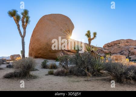 Sun setting behind dramatic rock formations in the Mojave Desert, Joshua Tree National Park, California, USA Stock Photo