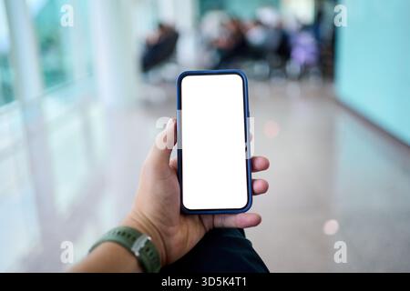 Male hand holding smartphone with blank screen at airport Stock Photo