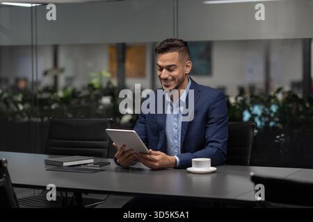 Young Middle Eastern Entrepreneur Using Digital Tablet to Manage Business Online in Modern Office Stock Photo