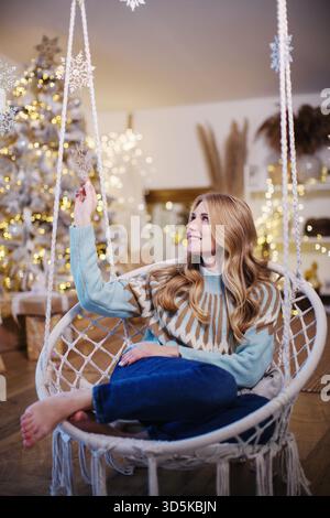 girl in Christmas sweaters enjoying cozy holiday moments at home with festive decor. Stock Photo