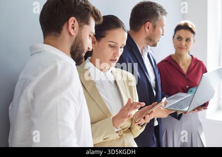 Office employees standing discussing online project, showing laptop computer presentation Stock Photo