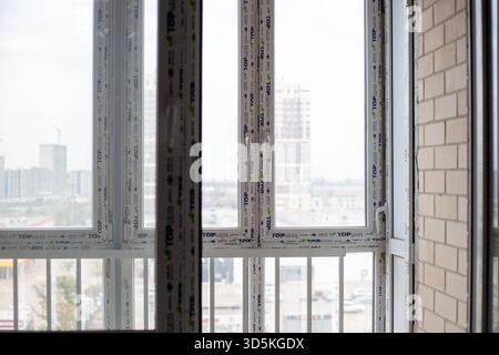 New TOP LINE PVC windows in a room under construction, with a blurred cityscape visible through the glass. Finishing work in a room in a new building. Stock Photo