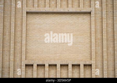 Large brick facade wall with advertisement space framed by architectural brickwork and line elements. Stock Photo