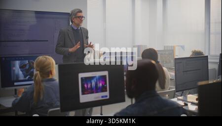 Stylish Male Instructor Stands by Monitor Showing Program, Explaining AI Generation Principles to Adult Students. Concept of Digital Education, Lifelong Learning, and Professional Development in Tech. Stock Photo