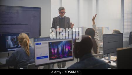 Stylish Male Instructor Stands by Monitor Showing Program, Explaining AI Generation Principles to Adult Students. Concept of Digital Education, Lifelong Learning, and Professional Development in Tech. Stock Photo
