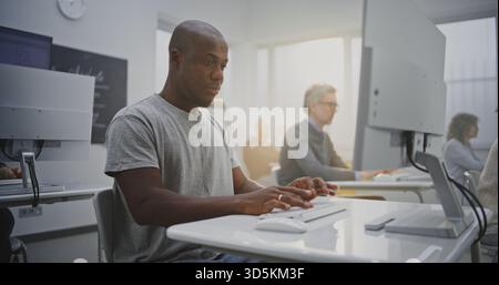 Cheerful African American Man Attends Programming Class, Smiling Brightly While Working on Computer. Concept Confidence, Digital Literacy, Professional Growth Through Technology Education. Portrait. Stock Photo