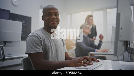 Cheerful African American Man Attends Programming Class, Smiling Brightly While Working on Computer. Concept Confidence, Digital Literacy, Professional Growth Through Technology Education. Portrait. Stock Photo