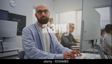 Bearded Mature Man in Computer Lab Attends Programming Lesson. Focused Yet Relaxed Expression Reflects Confidence and Motivation. Concept Continuous Learning, Technology Skills, and Growth. Portrait. Stock Photo