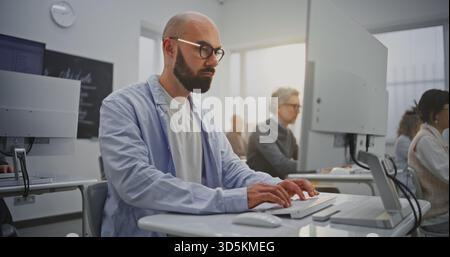 Bearded Mature Man in Computer Lab Attends Programming Lesson. Focused Yet Relaxed Expression Reflects Confidence and Motivation. Concept Continuous Learning, Technology Skills, and Growth. Portrait. Stock Photo