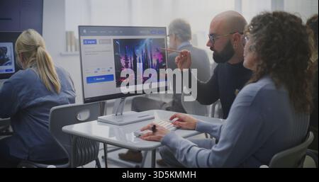 Young Teacher Guiding Adult Female Student Craft Effective Prompts For AI Image Generation During Digital Art Lesson. Man Analyzes Futuristic City Image on Screen. Concept of AI Education, Creativity. Stock Photo