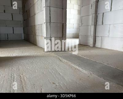 The interior of a private house, unfinished, in gray tones. Block walls and unfinished cement floors. Camera angle from below Stock Photo