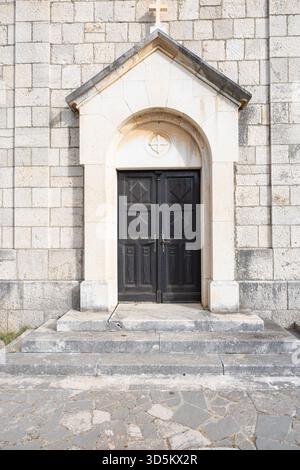 A weathered stone church. Green doors and rustic masonry evoke timeless rural architecture and quiet faith. Stock Photo