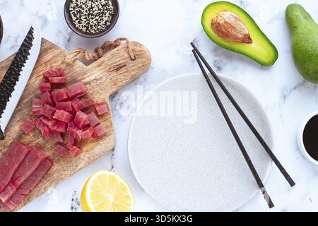 Cooking fresh tuna with ingredients on a marble countertop, ingredients for making sushi and tuna tartare Stock Photo