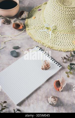 Notebook, beach hat, shells and stones on the table vertical view Stock Photo