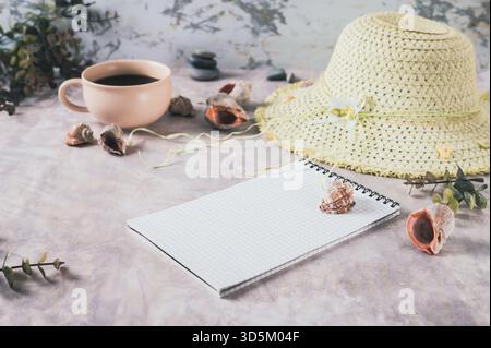 Notebook, beach hat, shells and stones on the table Stock Photo