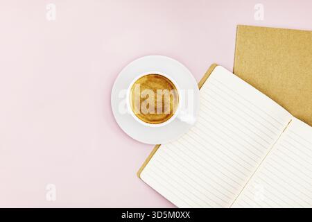 Top view mock-up close-up of two notebooks for writing and a white porcelain cup with coffee on a pink background. Selective focus Stock Photo