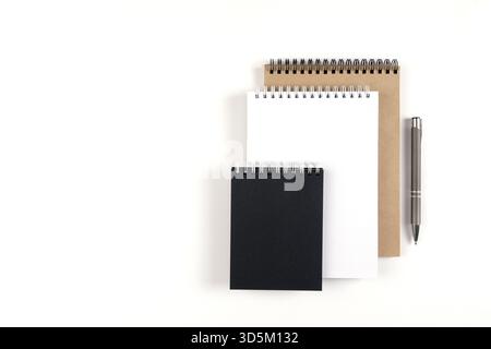 Three blank notepads on a spiral stacked in a stack on a white background. Notebooks with white, black and recycled sheets and pen. Education, office Stock Photo