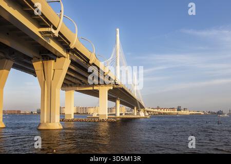 View of the bridge over the river with the expressway in the metropolis on a summer evening before sunset. Urban geometry Stock Photo