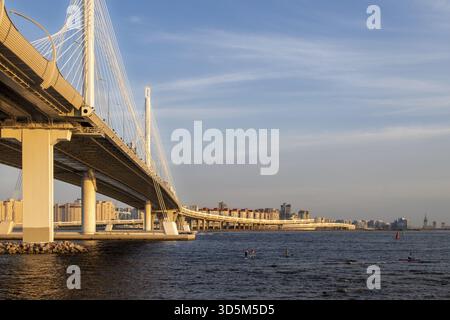 View of the bridge over the river with the expressway in the metropolis on a summer evening before sunset. Urban geometry Stock Photo
