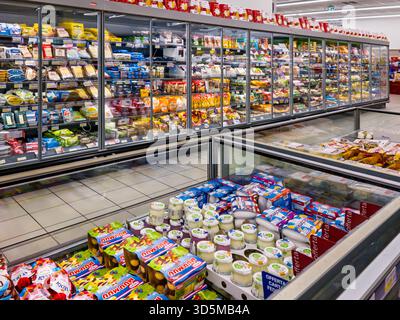 Italy - November 11, 2025: refrigerated cabinets and counters displaying packaged dairy products and cheeses of various brands in an Italian supermark Stock Photo
