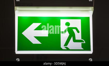 Illuminated emergency exit sign at night, glowing clearly in the darkness as a safety indicator. Stock Photo